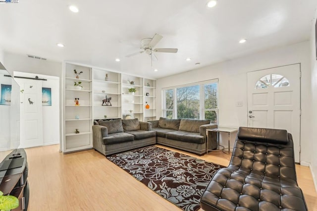 living room featuring a barn door, ceiling fan, and light wood-type flooring