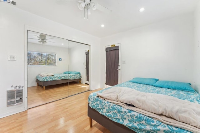 bedroom with hardwood / wood-style floors, a closet, heating unit, and ceiling fan