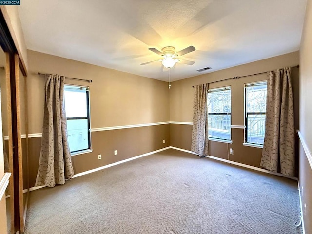 carpeted empty room featuring ceiling fan and a wealth of natural light