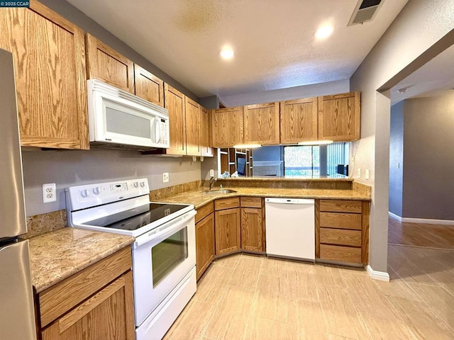 kitchen with white appliances, a textured ceiling, and sink