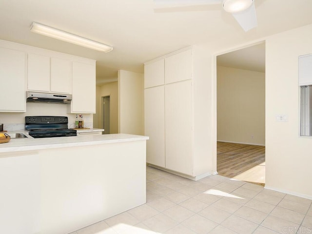 kitchen featuring black electric range, light tile patterned floors, and white cabinets