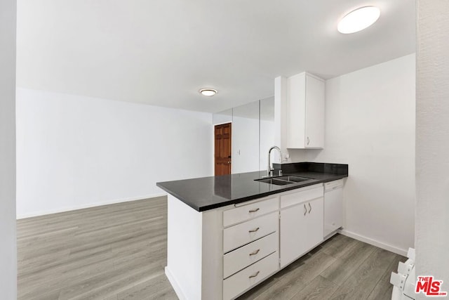 kitchen with dishwasher, sink, light hardwood / wood-style flooring, white cabinetry, and kitchen peninsula