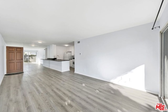 unfurnished living room featuring light hardwood / wood-style floors and sink