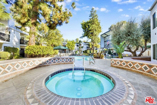 view of swimming pool with a patio area and a community hot tub