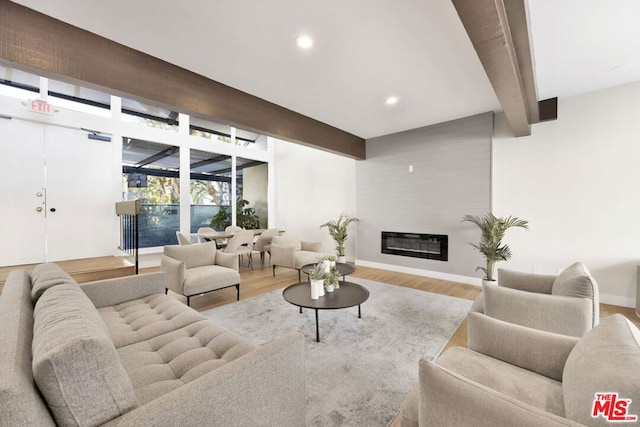 living room featuring beam ceiling, a fireplace, and hardwood / wood-style flooring