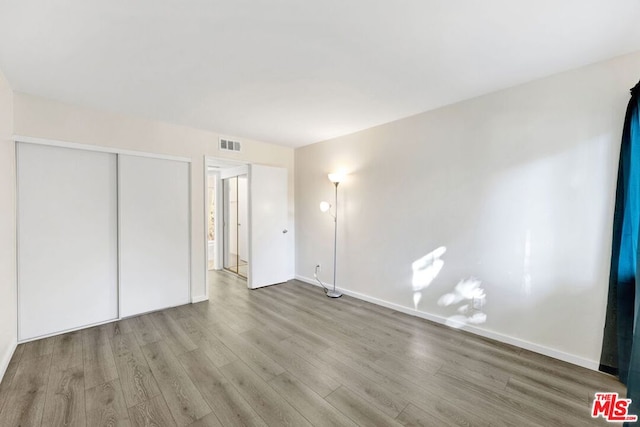 unfurnished bedroom with a closet and light wood-type flooring