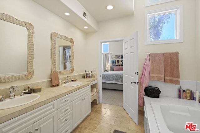 bathroom with a tub to relax in, vanity, and tile patterned floors