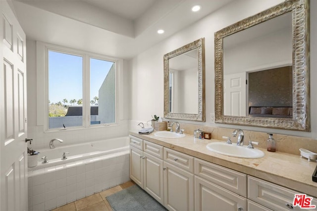 bathroom with tiled bath, tile patterned flooring, and vanity