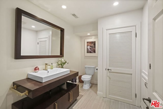 bathroom with toilet, hardwood / wood-style flooring, and vanity