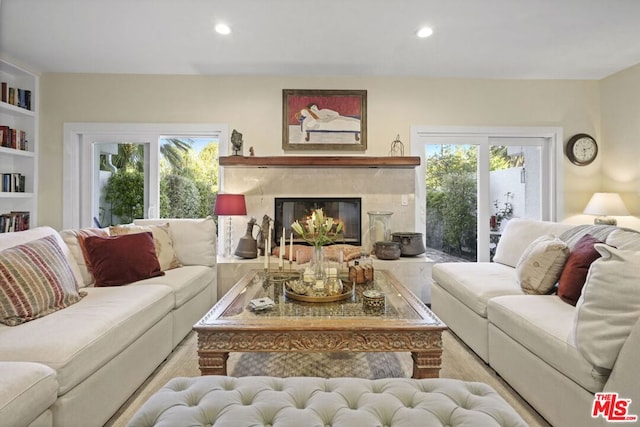 living room with built in features, a healthy amount of sunlight, and a fireplace