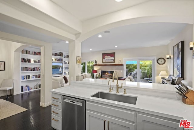 kitchen with stainless steel dishwasher, built in shelves, dark hardwood / wood-style flooring, and sink