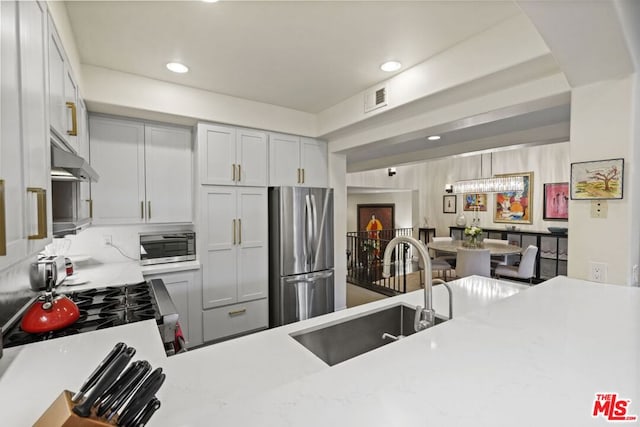 kitchen with stainless steel appliances, kitchen peninsula, light stone counters, and sink