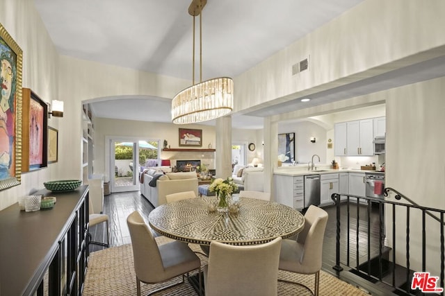 dining area featuring dark wood-type flooring, sink, and a notable chandelier