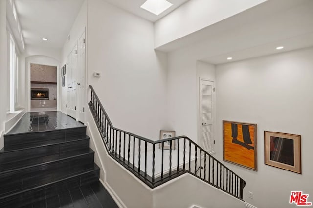 stairway with a premium fireplace, a skylight, and hardwood / wood-style floors