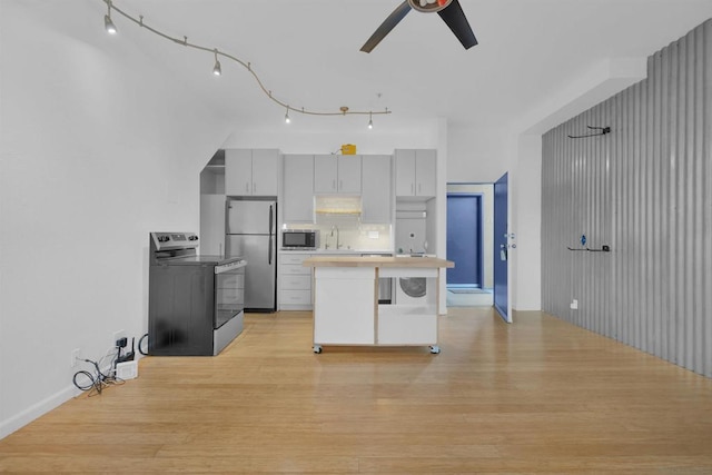 kitchen with gray cabinetry, backsplash, ceiling fan, stainless steel appliances, and light hardwood / wood-style flooring