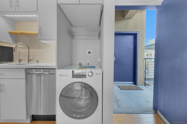 clothes washing area featuring washer / clothes dryer, light hardwood / wood-style floors, and sink