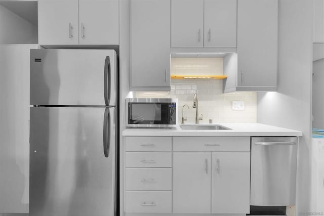 kitchen featuring white cabinetry, stainless steel appliances, sink, and backsplash