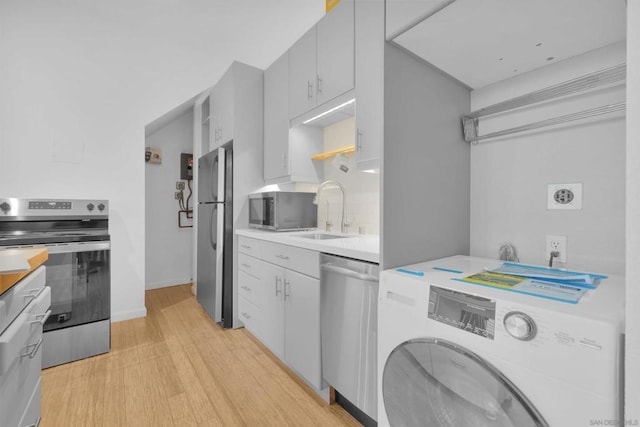 kitchen featuring washer / clothes dryer, appliances with stainless steel finishes, sink, and light hardwood / wood-style floors