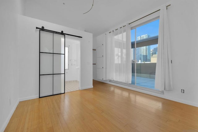 empty room with a barn door and light wood-type flooring