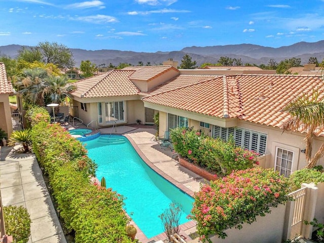 view of swimming pool featuring a patio area, a mountain view, and an in ground hot tub