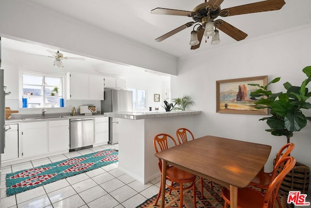 dining space featuring light tile patterned flooring, plenty of natural light, crown molding, and sink