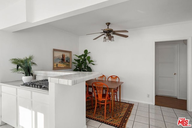 kitchen featuring tile counters, white cabinetry, crown molding, and light tile patterned floors