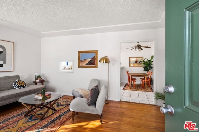 living room with ceiling fan, hardwood / wood-style floors, and a textured ceiling