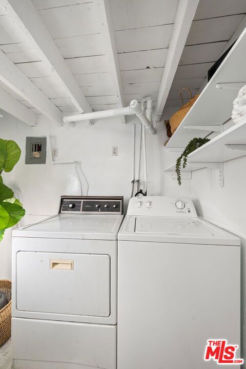 laundry room with washing machine and dryer, wooden ceiling, and electric panel