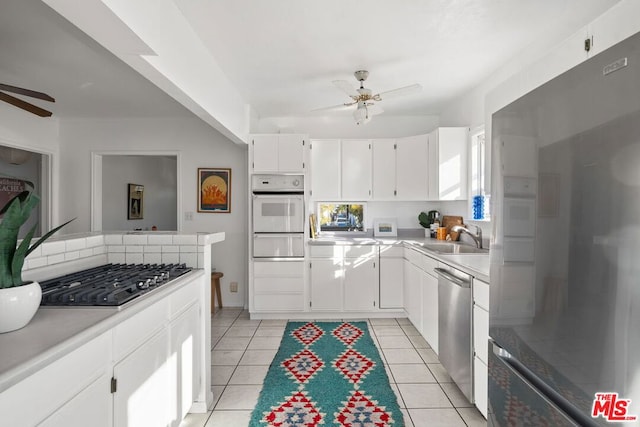 kitchen with ceiling fan, sink, light tile patterned floors, white cabinets, and appliances with stainless steel finishes