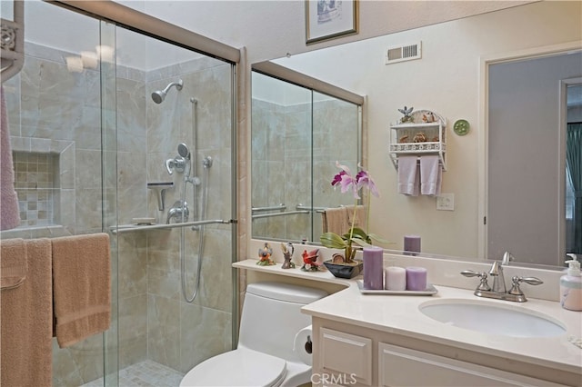 bathroom featuring toilet, vanity, and a shower with door