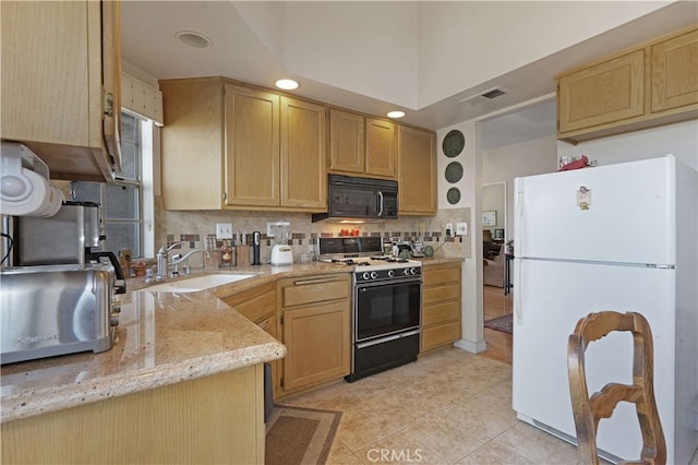 kitchen with gas stove, sink, light brown cabinetry, light stone counters, and white refrigerator