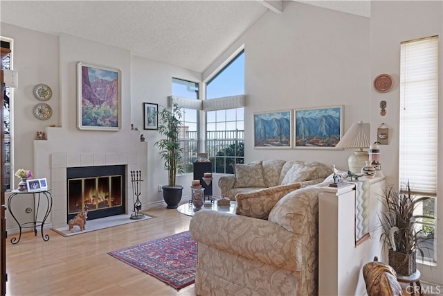 living room with a fireplace, wood-type flooring, high vaulted ceiling, a textured ceiling, and beamed ceiling