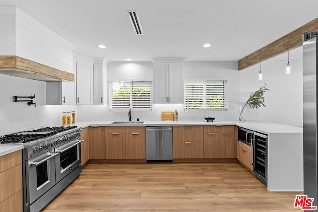 kitchen with custom range hood, stainless steel appliances, white cabinetry, and sink