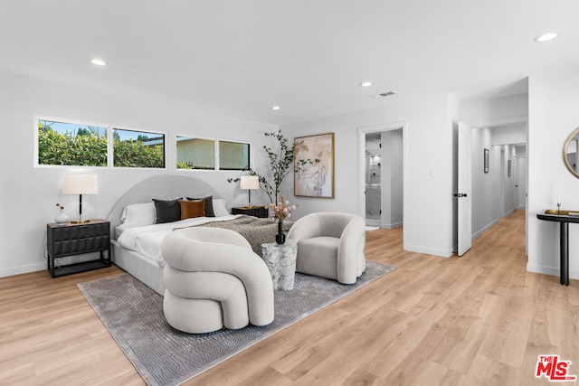 bedroom featuring ensuite bathroom and light hardwood / wood-style flooring