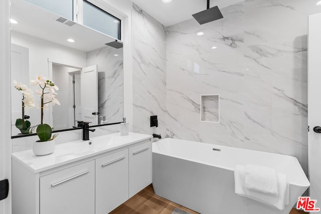 bathroom with vanity, hardwood / wood-style flooring, tile walls, and independent shower and bath