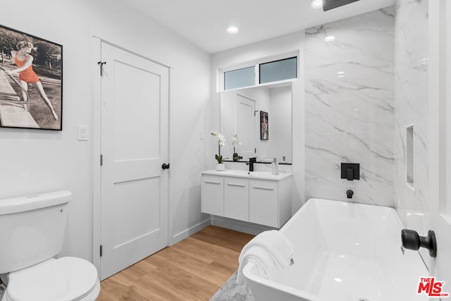 bathroom with vanity, hardwood / wood-style flooring, toilet, and a tub