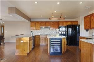 kitchen featuring black appliances, decorative backsplash, dark hardwood / wood-style floors, range hood, and a kitchen island