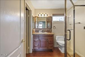 bathroom with hardwood / wood-style floors, vanity, a shower with shower door, and toilet