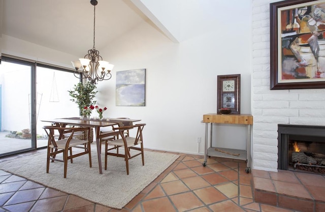 dining space featuring a tile fireplace, an inviting chandelier, and lofted ceiling