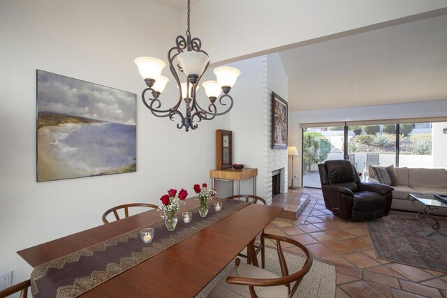 dining space featuring a fireplace, lofted ceiling, and a notable chandelier