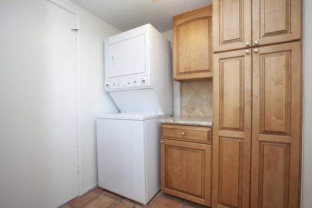 washroom with cabinets and stacked washing maching and dryer