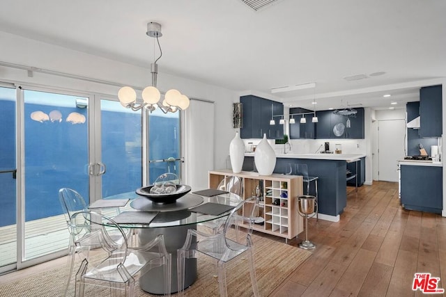 dining area with hardwood / wood-style floors, a healthy amount of sunlight, and a notable chandelier