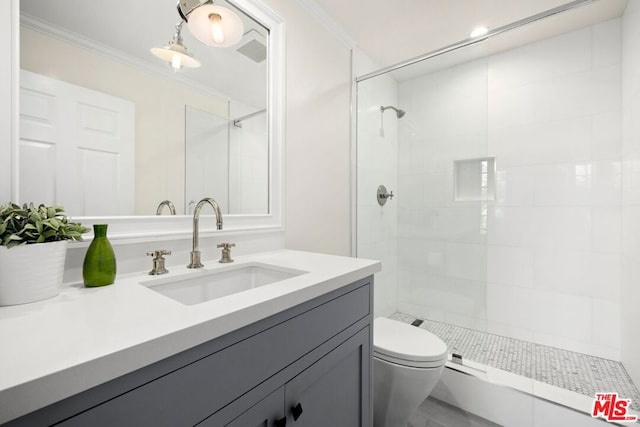 bathroom with a tile shower, toilet, vanity, and ornamental molding