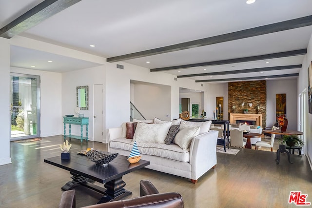 living room featuring beamed ceiling, a stone fireplace, and hardwood / wood-style flooring