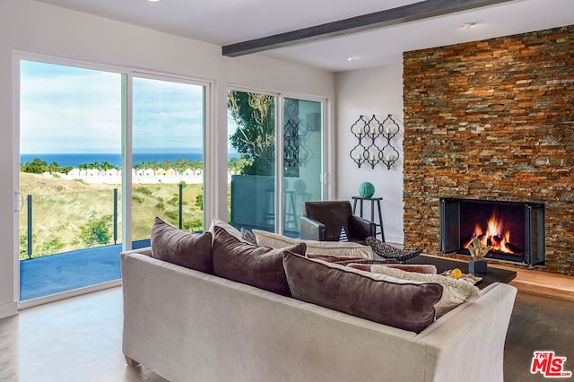 living room featuring beamed ceiling, a stone fireplace, and a water view