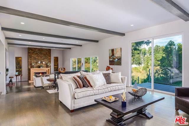 living room with dark hardwood / wood-style floors, beam ceiling, and a stone fireplace