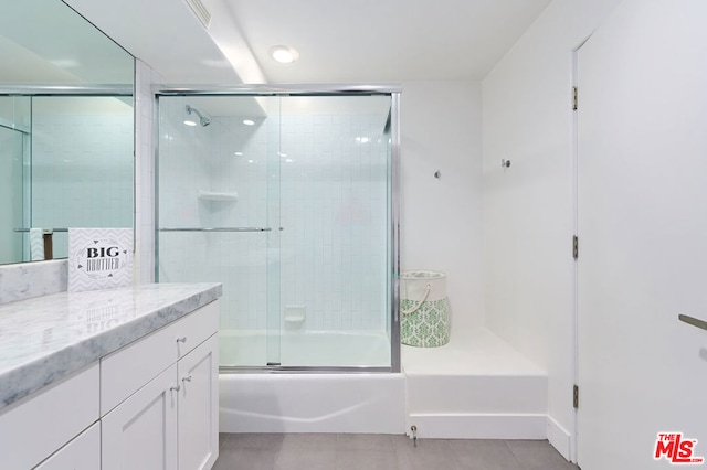 bathroom featuring tile patterned flooring, vanity, and shower / bath combination with glass door