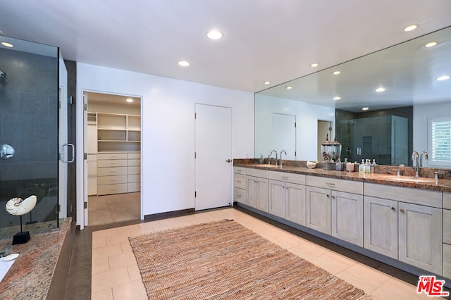 bathroom featuring tile patterned floors, a shower with door, and vanity