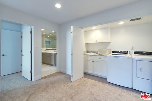 laundry area featuring light carpet, sink, cabinets, and washing machine and clothes dryer