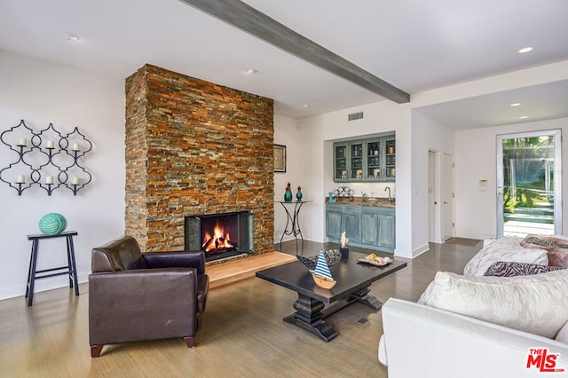 living room with a fireplace, beamed ceiling, wood-type flooring, and wet bar